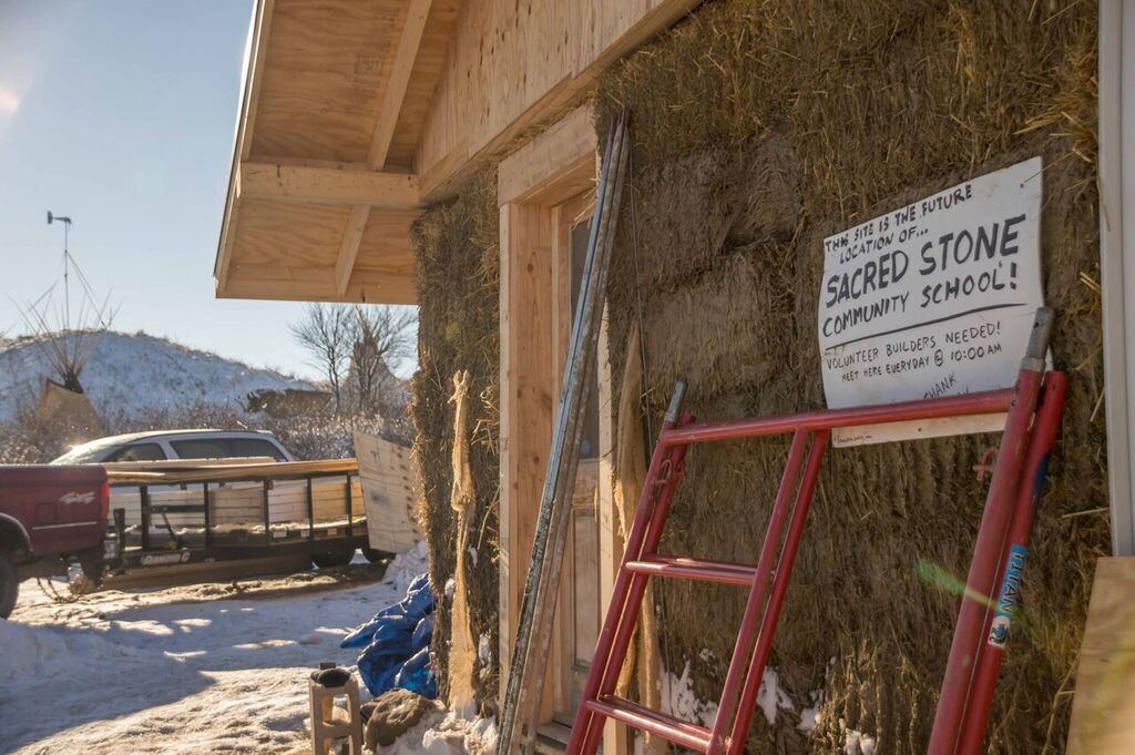 Construction of the Sacred Stone Community School at the Standing Rock encampment, with a "Volunteer Builders Needed" sign
